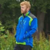 Mann in Blauer Forstjacke steht vor einem Wald