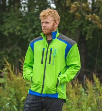 Mann in grüner Forstjacke steht vor einem Wald