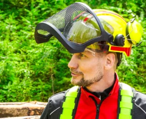 Mann trägt Forsthelm mit offenem Visier im Wald