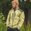 Mann in beiger Forstjacke steht vor einem Wald