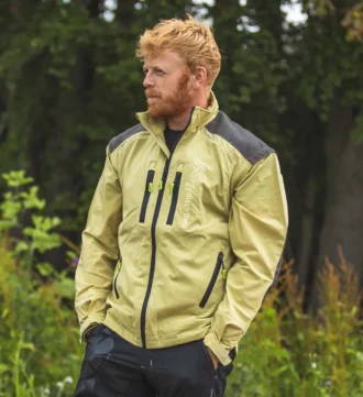 Mann in beiger Forstjacke steht vor einem Wald