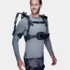 Dreiviertelansicht eines Mannes in grauem Oberteil und grauer Hose, der ein schwarzes Auxivo OmniSuit Exoskelett trägt, das seine Schultern, seinen Rücken und seine Hüften unterstützt.