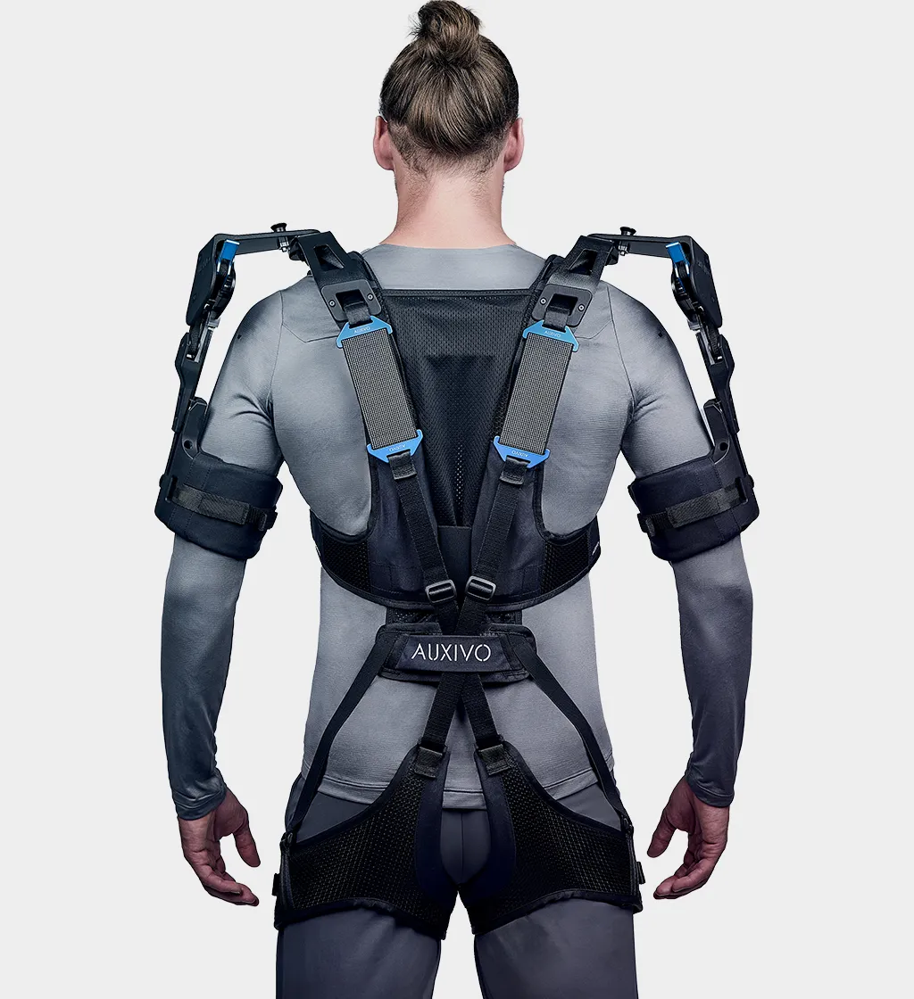 Rückansicht eines Mannes in grauem Oberteil, der ein schwarzes Auxivo OmniSuit Exoskelett trägt, das seinen Rücken, seine Schultern und Hüften unterstützt