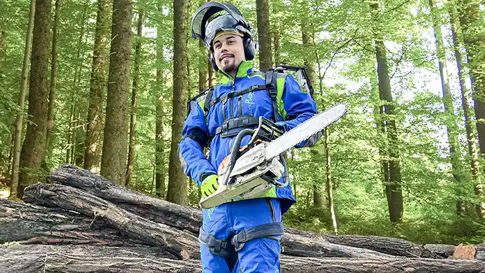 Rückansicht eines Mannes in grauem Oberteil, der ein schwarzes Auxivo OmniSuit Exoskelett trägt, das seinen Rücken, seine Schultern und Hüften unterstützt
